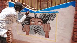 A student painting a mural in Khartoum, Sudan