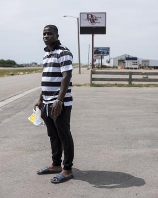 A man stands along the road