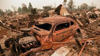 Разрушенный автомобиль виден среди руин сгоревшего квартала после того, как пожар Карра прошел через район поместья Кесвик возле Реддинга, штат Калифорния, 28 июля 2018 года