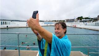 Woman taking selfie beside Penzane open air pool which has just reopened after lockdown