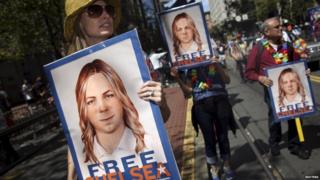 People hold signs calling for the release of imprisoned wikileaks whistleblower Chelsea Manning while marching in a gay pride parade in San Francisco, California on 28 June 2015.