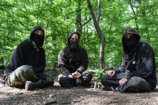 Três ativistas com capuz na floresta