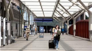 Woman with mask under her chin walking through very empty Paddington station