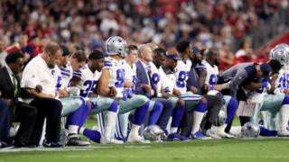 Jugadores de los Vaqueros de Dallas se arrodillan durante el himno de EE.UU.