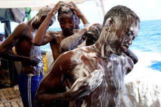 Migrants take a shower on board the NGO Proactiva Open Arms rescue boat in central Mediterranean Sea