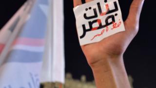 يد ولافتة مكتوب عليها "النساء خط أحمر"