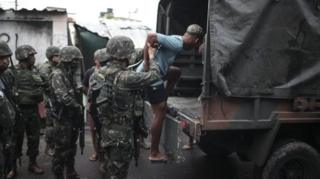 Homem é colocado em caminhão do Exército