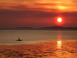 Man in sea kayak during Ullapool sunset