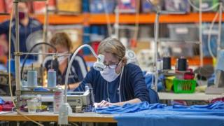 A masked worker making NHS scrubs