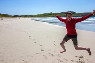Boy jumping for joy on Vatersay beach