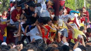 Catholics stand on each others' shoulders to try to touch the statue in Manila (9 Jan 2019)