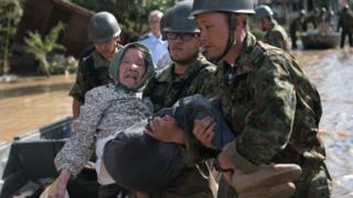 Soldiers carry an elderly woman to a vehicle to be evacuated after rescuing her following heavy flooding