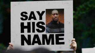 Protestor holding a placard with picture of George Floyd