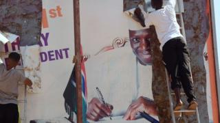 Workers remove an electoral poster of Gambia's President Yahya Jammeh, in a street of Bijilo, on 4 December 2016 after he initially accepted defeat