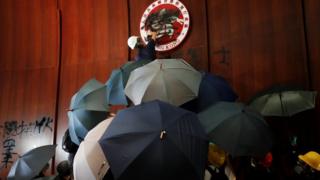 A protester sprays graffiti on the Hong Kong emblem in the chamber of parliament