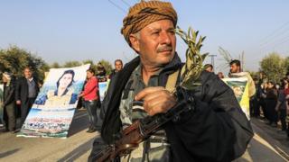 Kürt bir savaşçı, Türkiye'nin Afrin'deki operasyonlarına karşı yapılan protestoya elinde tüfeği ve zeytin dalıyla katılırken