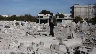 A man walks past a graveyard in Deir al-Asafir, outside Damascus, Syria (25 November 2015)