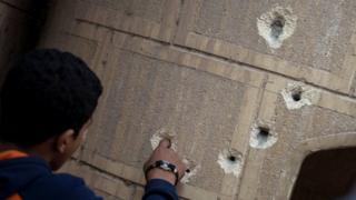 Wani mutum na duba ramukan harbi a jikin cocin Mar Mina bayan harin da aka kai a gundumar Helwan na birnin Alka'ira.