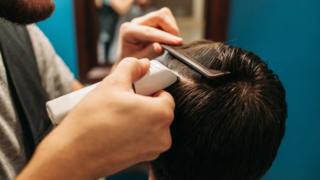 Un hombre le rapa la cabeza a otro