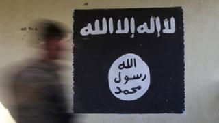 A member of the Iraqi rapid response forces walks past a wall painted with the black flag commonly used by Islamic State militants, at a hospital damaged by clashes during a battle between Iraqi forces and Islamic State militants in the Wahda district of Mosul, Iraq,