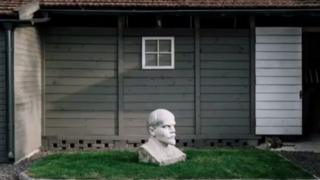 Un busto de Vladimir Lenin frente a una casa