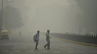 Two pedestrians on road in New Delhi engulfed in smog from last year
