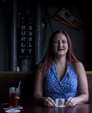 A woman holds a picture of herself