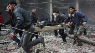 Rescuers carry a badly injured man in a stretcher after a reported air strike on the town of Kafr Batna, in the Eastern Ghouta area outside Damascus (6 February 2018)