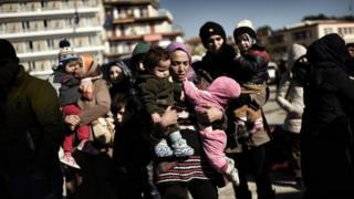 Women carry babies after arriving with other refugees and migrants in Mytilene, the port of the northern island of Lesbos, on 22 February 2016