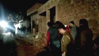 Residents and police outside the building where a man has held hostages in Farrukhabad
