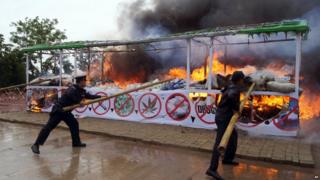 Members of Myanmar fire brigade poke burning narcotic drugs with sticks during a destruction ceremony of seized narcotic drugs in outskirts of Yangon on 26 June