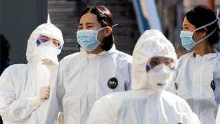 Medical staff members wearing protective gear arrive for their shift to care for patients infected with the COVID-19 coronavirus, at a hospital in Daegu on March 11, 2020.