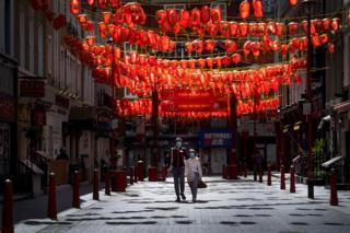 A couple wearing face masks walk through Chinatown