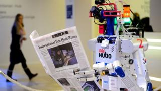 Робот держит газету во время демонстрации во время ежегодной встречи Всемирного экономического форума (ВЭФ) в Давосе, 22 января 2016 года.