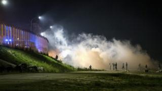 Migrants clash with French riot police as they attack the fence next to the makeshift Jungle camp in Calais (22 October 2016)