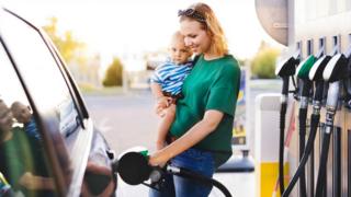 Mother holding baby at petrol pump