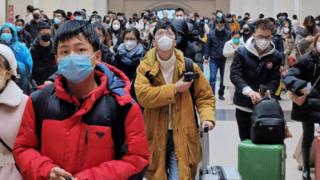 Люди в масках ждут на вокзале Ханькоу в Ухане, Китай.