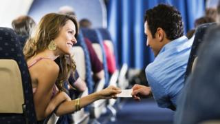 Mulher e homem a bordo de avião, trocando telefones