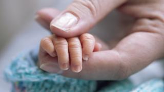 Мать держит руку новорожденного