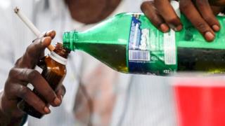 Man pouring cough syrup into a bottle