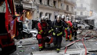 Firefighters carry an injured person after the explosion of a bakery on the corner of the streets Saint-Cecile and Rue de Trevise in central Paris on January 12, 20