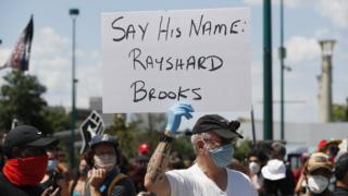 A protester holds a sign with Rayshard Brooks' name in Atlanta