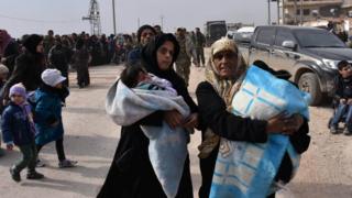 Две женщины сжимают свои вещи, когда они покидают восточный Алеппо