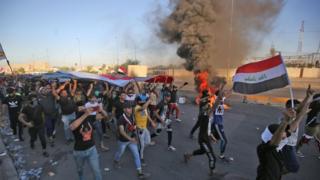محتجون يرفعون العلم العراقي في وسط بغداد.