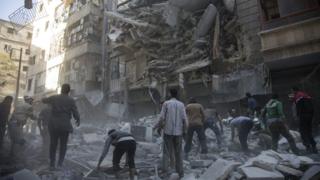 Сирийские гражданские лица и спасатели разыскивают выживших после ударов с воздуха в мятежном районе Аль-Шаар в Алеппо, 27 сентября 2016 года
