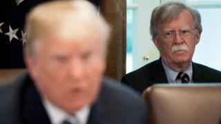 John Bolton (R) mira a Donald Trump (L) (9 de mayo de 2018)