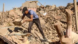 Volunteers search the rubble of collapsed houses in Tafeghaghte
