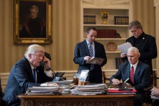 El presidente de EE.UU., Donald Trump, habla por teléfono desde el Despacho Oval de la Casa Blanca con el presidente ruso, Vladimir Putin, rodeado (de izquierda a derecha) del jefe de personal de la Casa Blanca Reince Priebus, el vicepresidente Mike Pence (sentado), y su estratega jefe, Stephen Bannon.