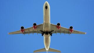 Аэробус Virgin Atlantic Airways A340-642 (позывной G-VFOX) развертывает свое шасси на подходе к аэропорту Хитроу, вид снизу траектории полета в Барнсе, юго-западная часть Лондона, 14/07/2009