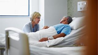 Woman holding man's hand in hospital